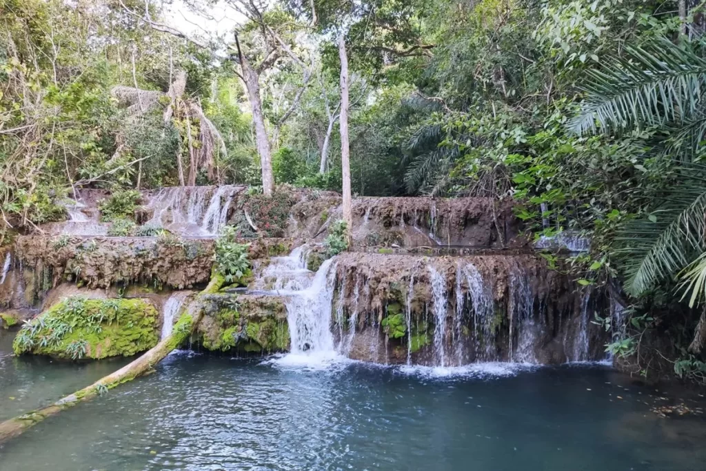 Cachoeira de Bonito com vários níveis de quedas d’água sobre rochas cobertas por musgos e plantas, cercada por mata densa