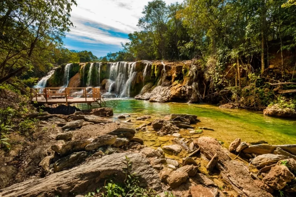 Cachoeira com águas cristalinas e plataforma de madeira em meio à mata nativa