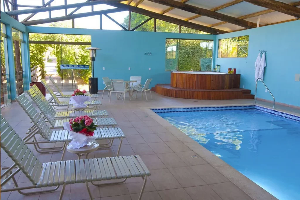 Hotel Pousada Águas de Bonito com piscina coberta, espreguiçadeiras e banheira de hidromassagem.